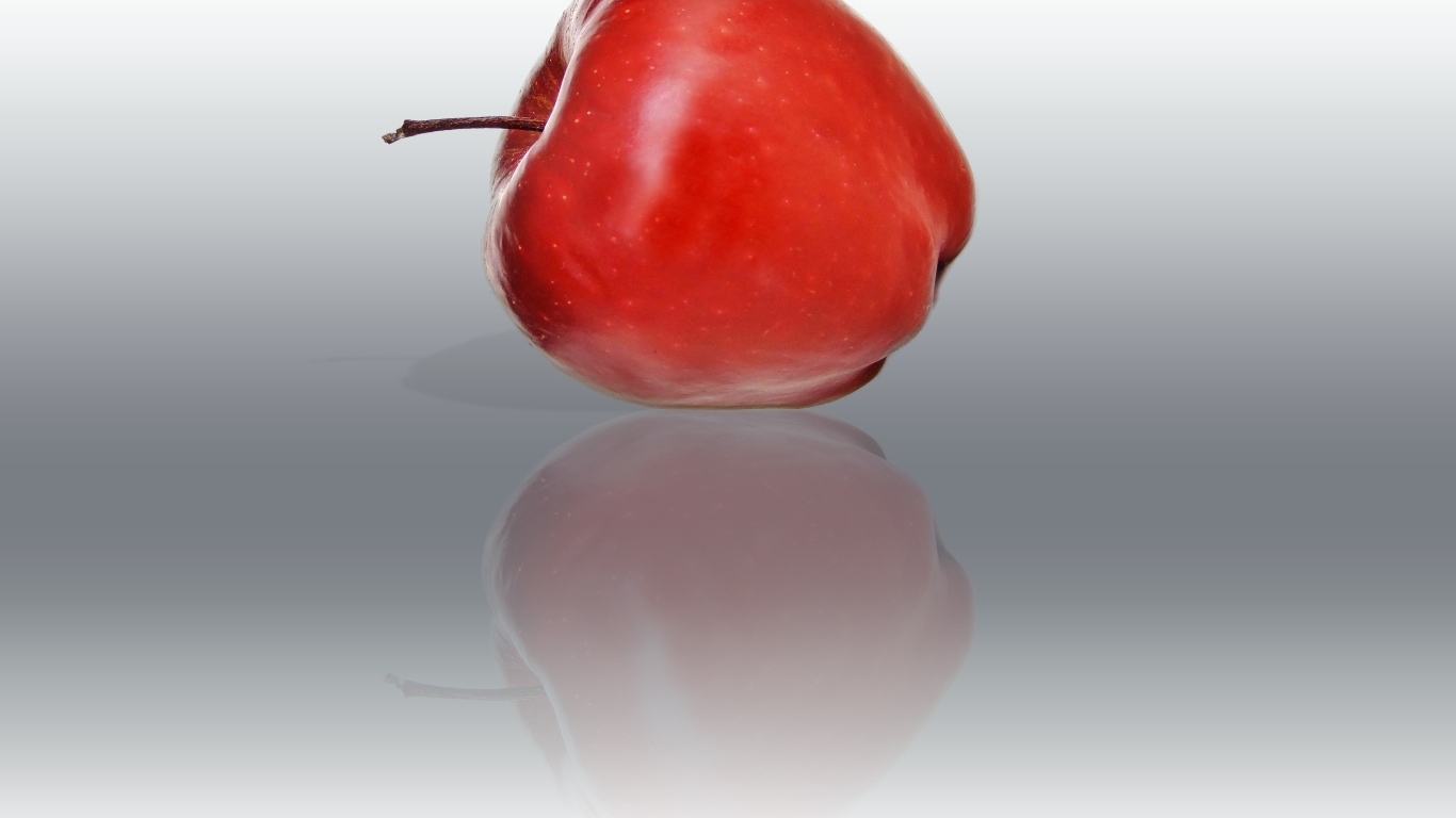 Красное яблоко отражается в серой поверхности