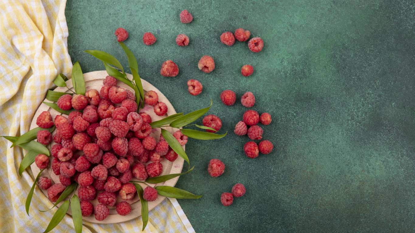 Красная малина с зеленой листвой на столе