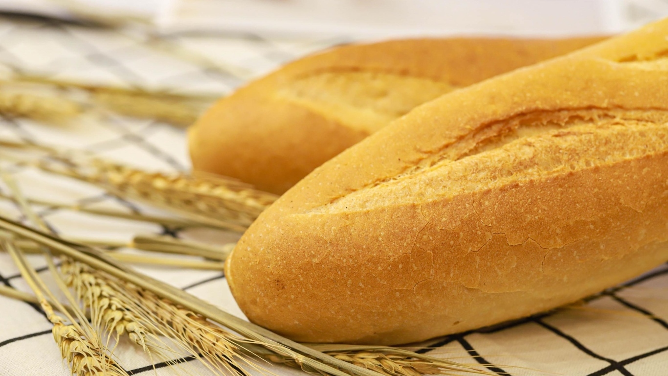 Два батона на столе с колосьями пшеницы