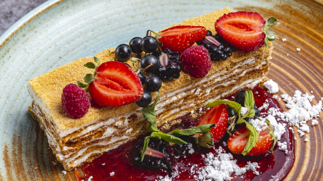 Большой кусок медового торта с ягодами