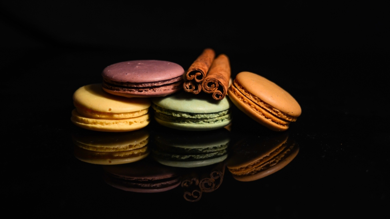 Десерт макарон с корицей на черном фоне