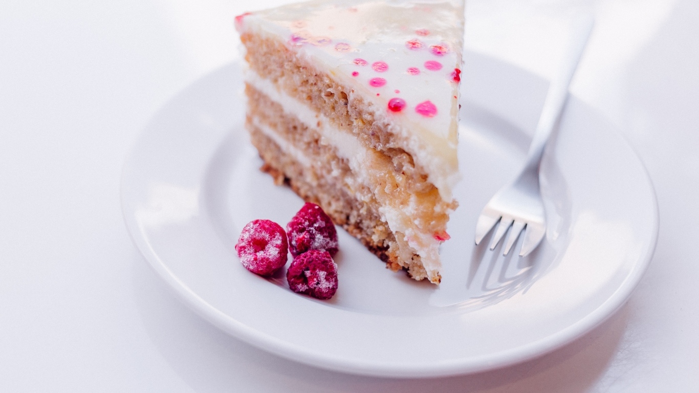 Кусок торта с замороженной малиной на белой тарелке