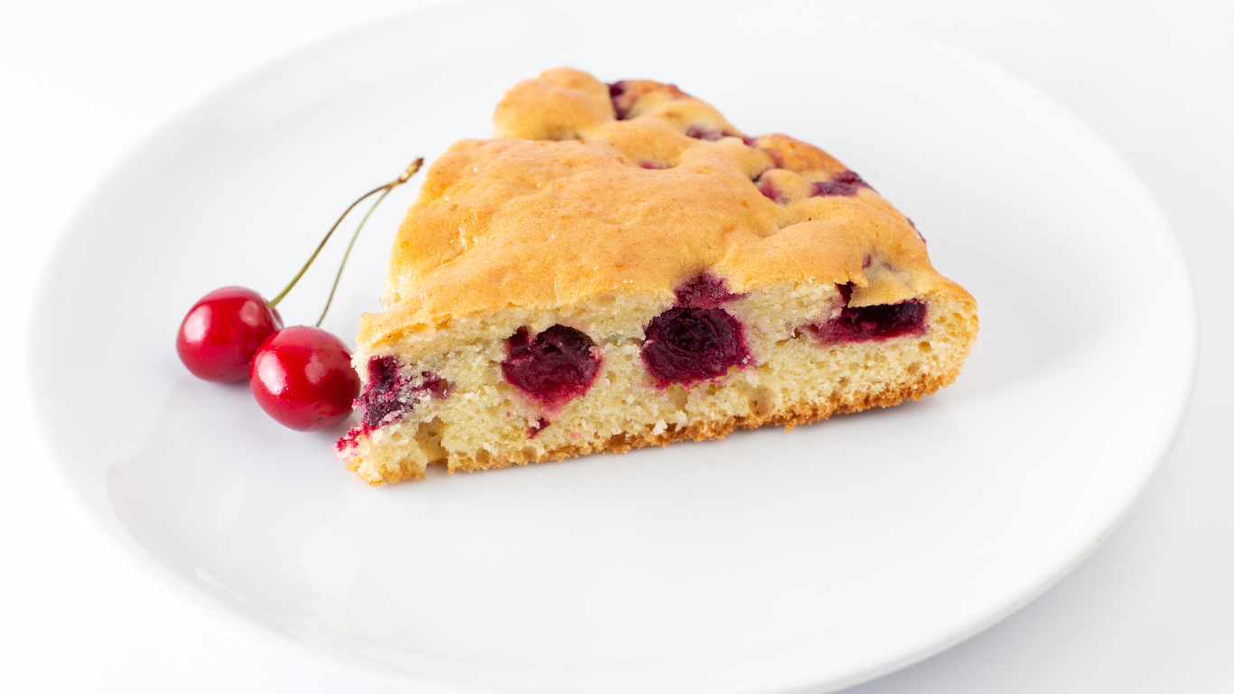 Кусок вишневого пирога с ягодами на тарелке