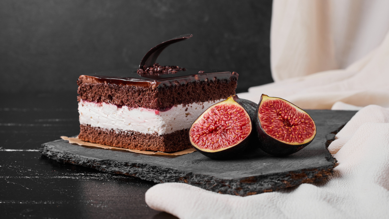 Кусок шоколадного торта с половинками инжира на столе