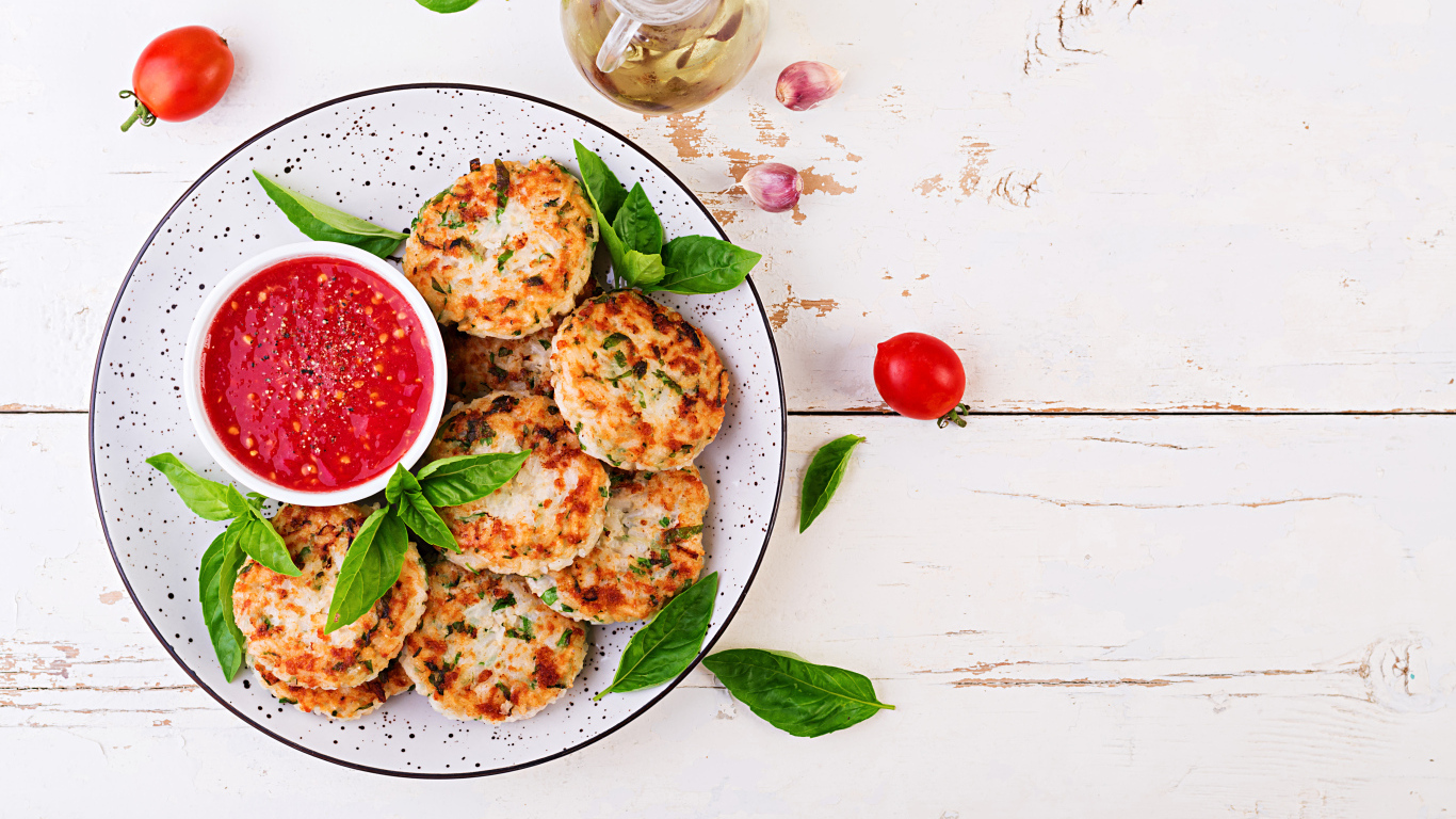 Куриные котлеты на большой белой тарелке  с соусом