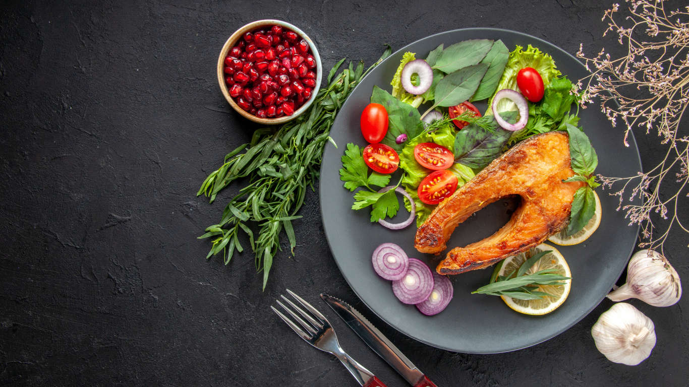 Жареная рыба на тарелке с овощами и зеленью