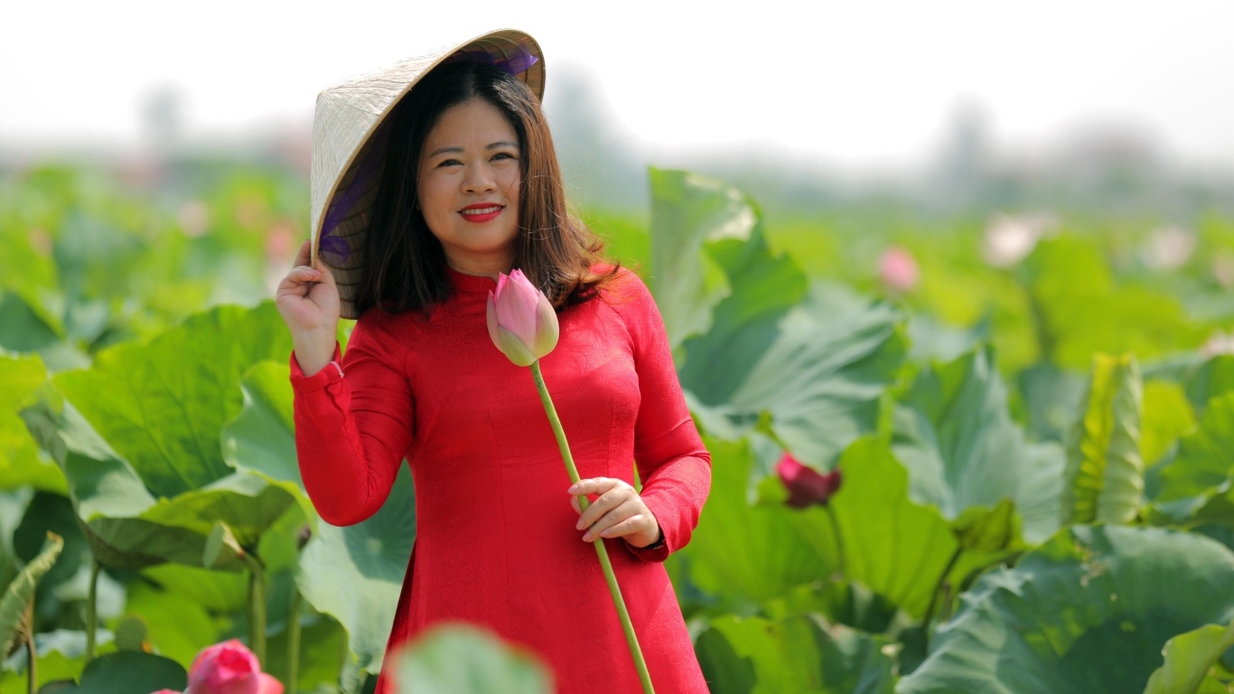 Девушка азиатка в красном платье у цветов лотоса