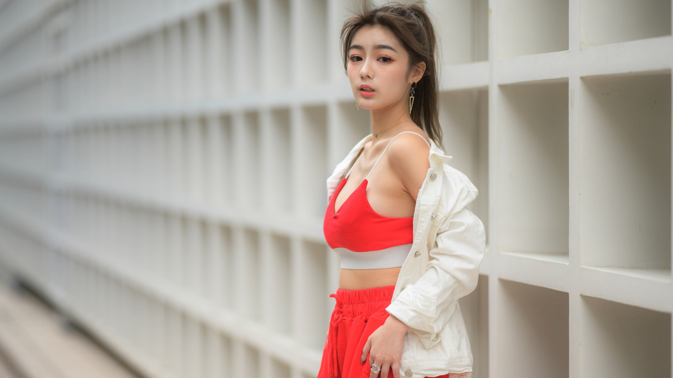 Азиатка в красном спортивном костюме стоит у стены