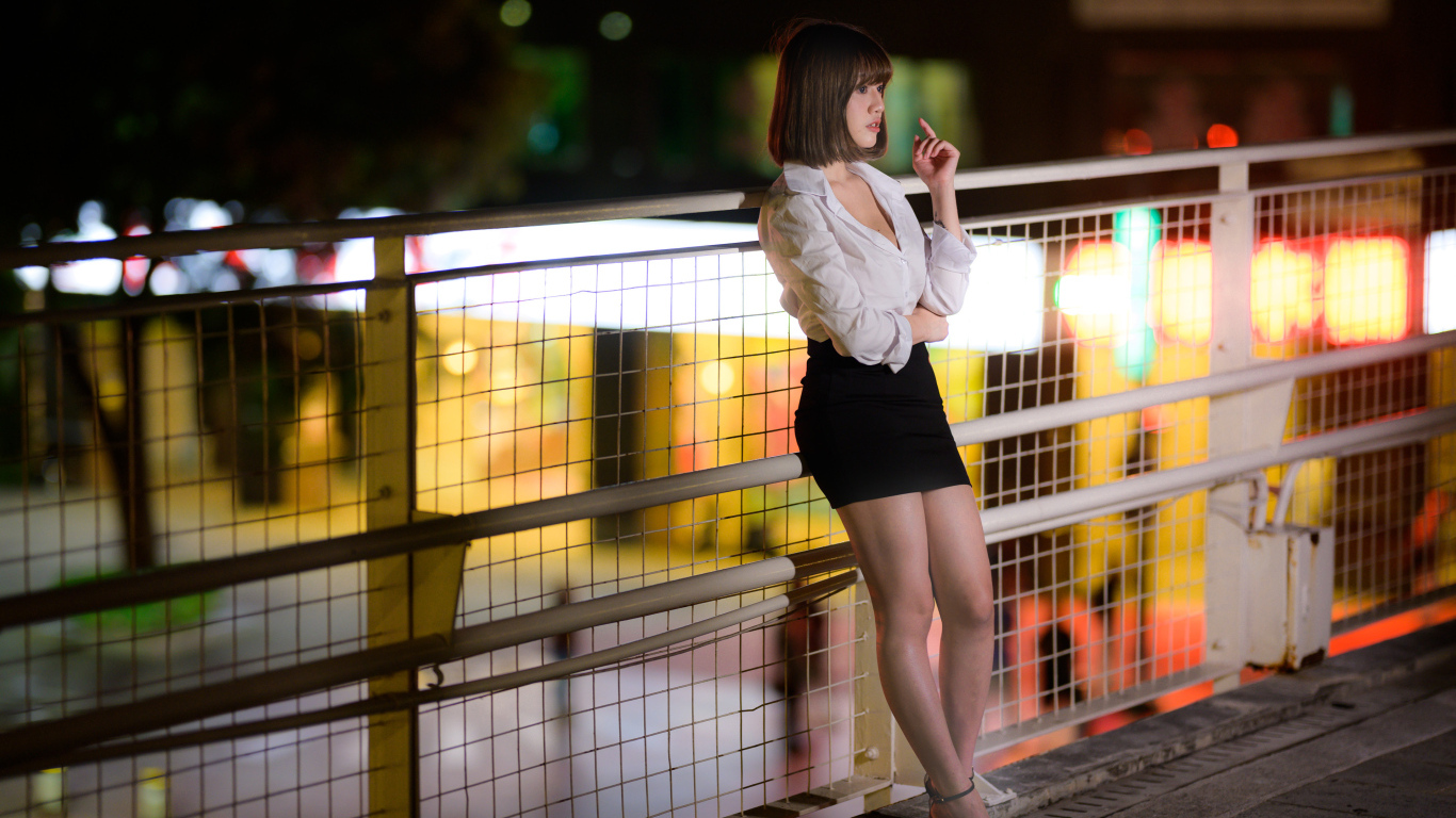 Азиатка в короткой черной юбке позирует для фото