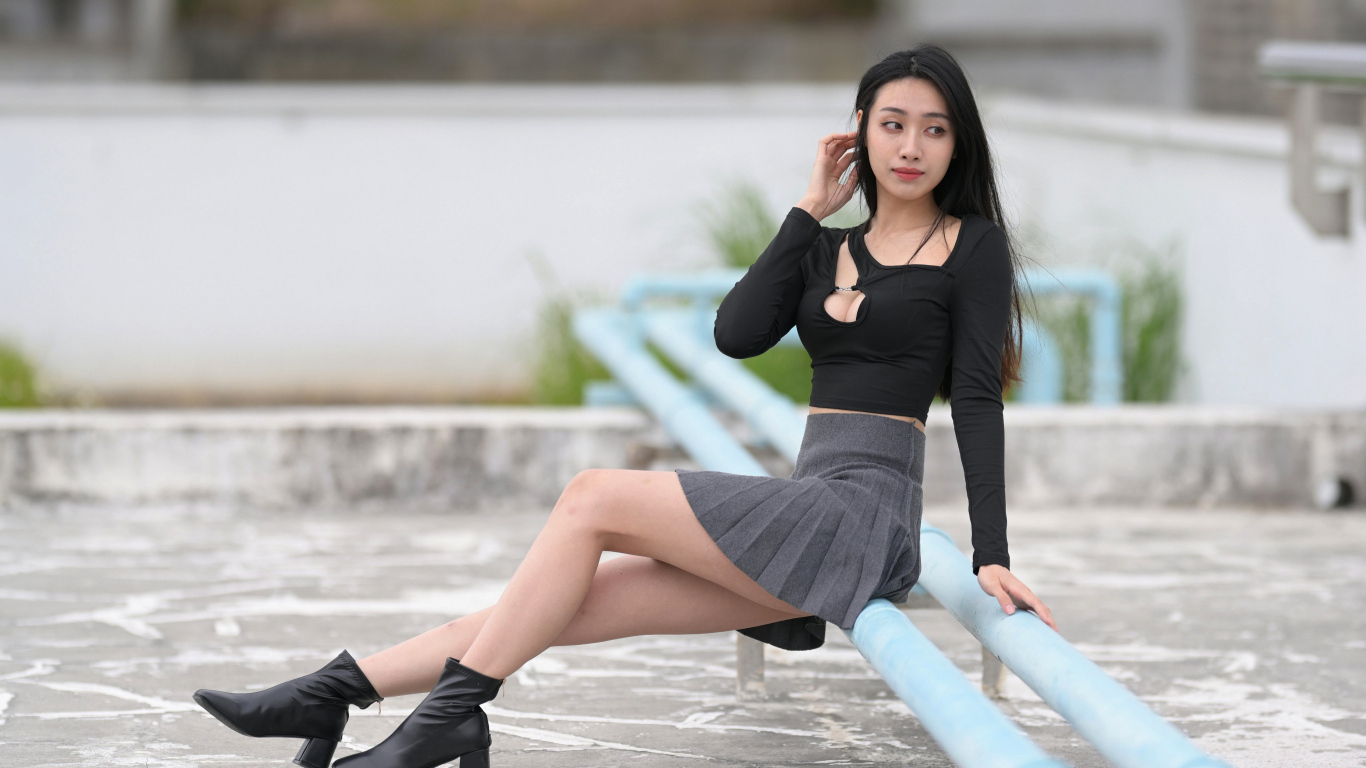 Азиатка в короткой юбке сидит на трубе