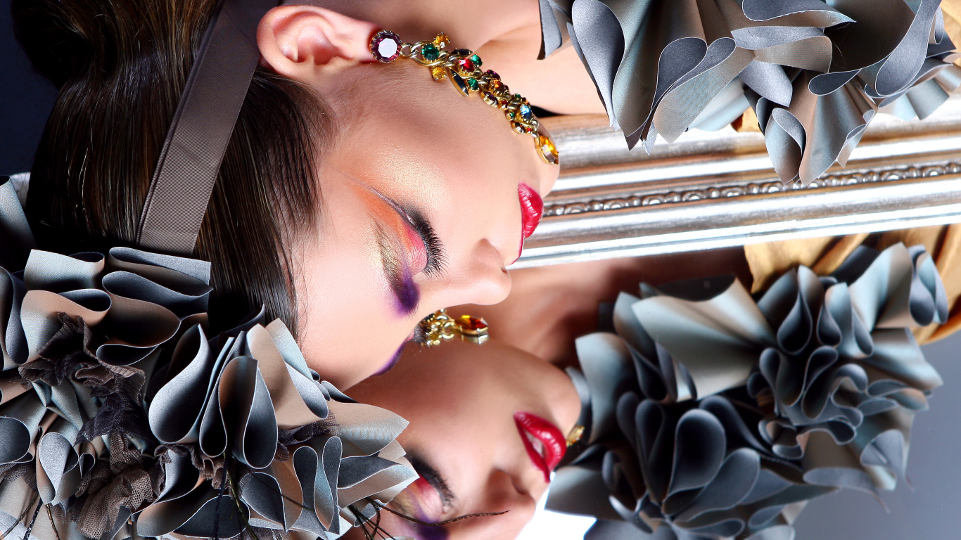 Красивая девушка с ярким макияжем отражается в зеркале