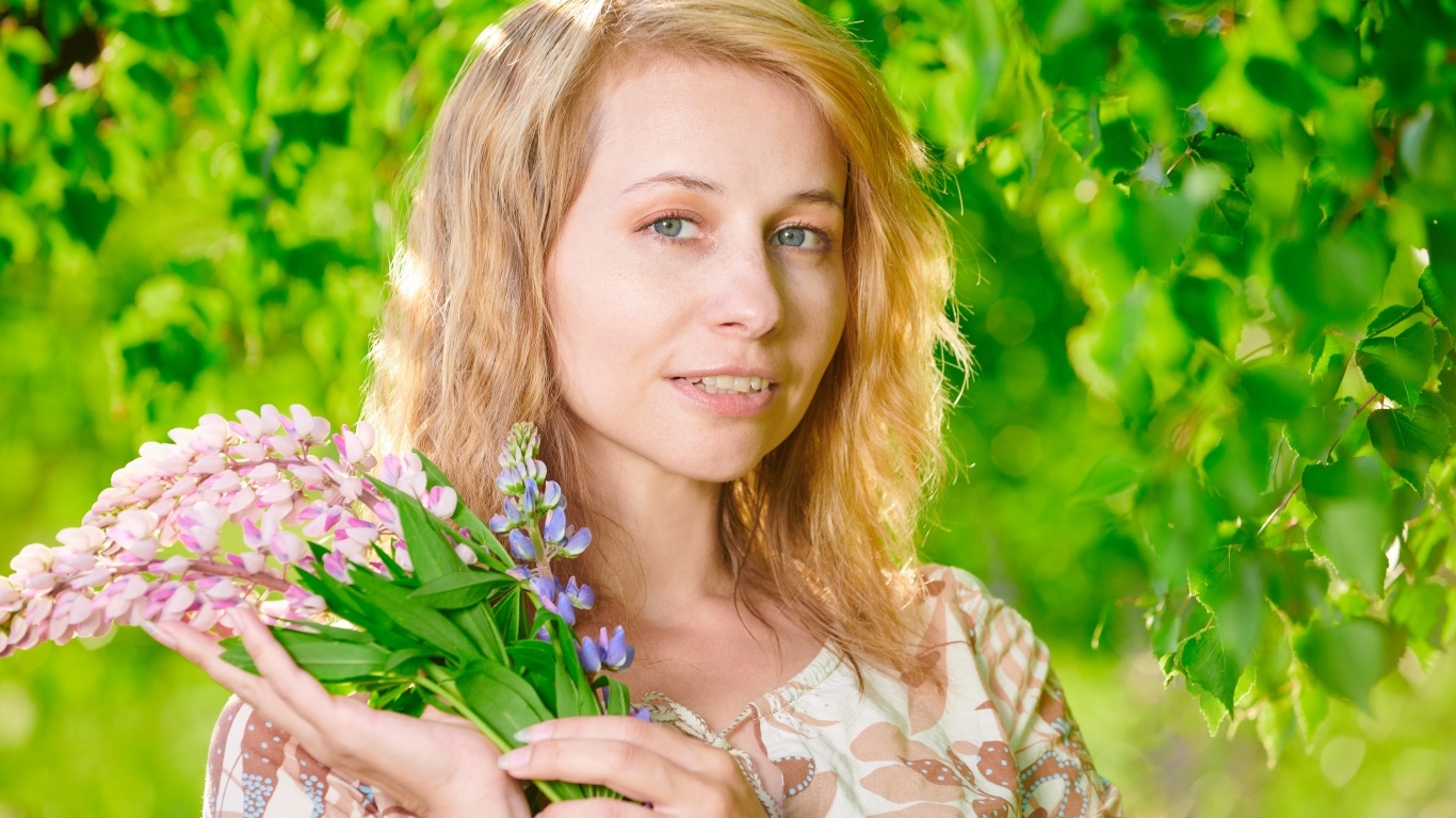 Красивая девушка с цветами люпина в руке