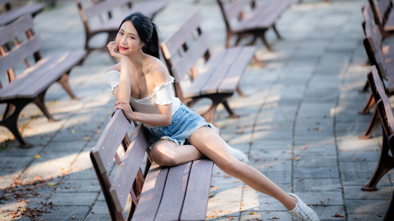 Милая девушка азиатка сидит на лавке в парке