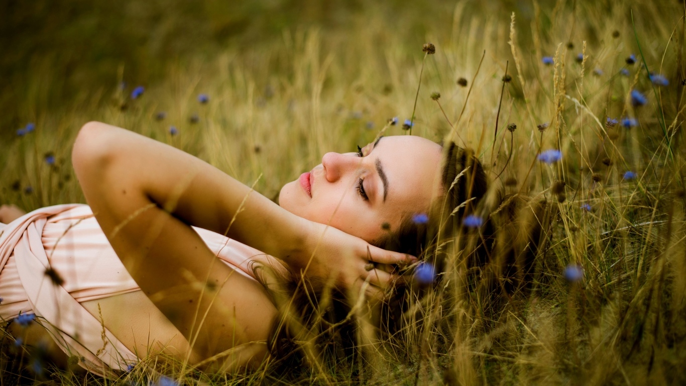 Милая девушка лежит на траве на поле