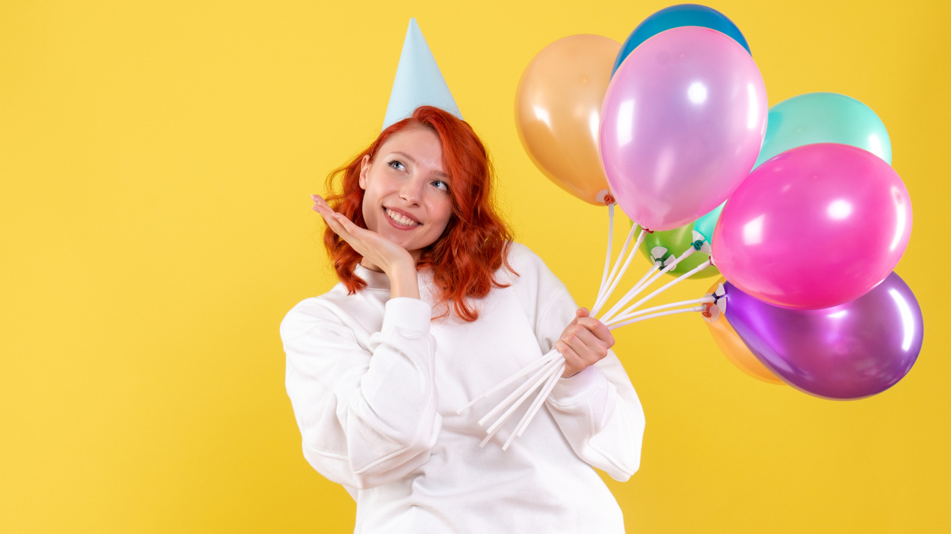 Милая рыжеволосая девушка с шариками на желтом фоне