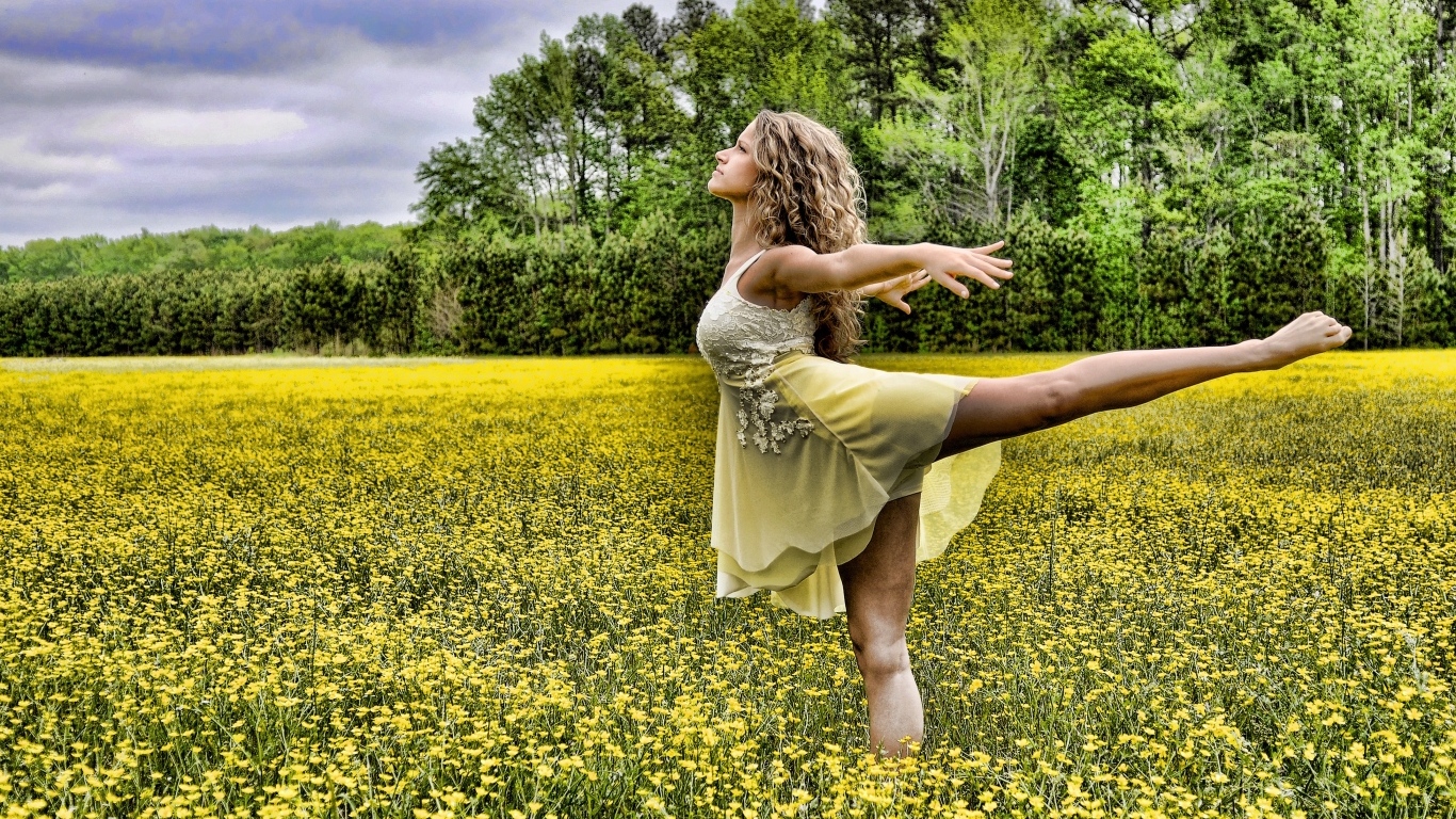 Девушка танцует на поле с желтыми цветами