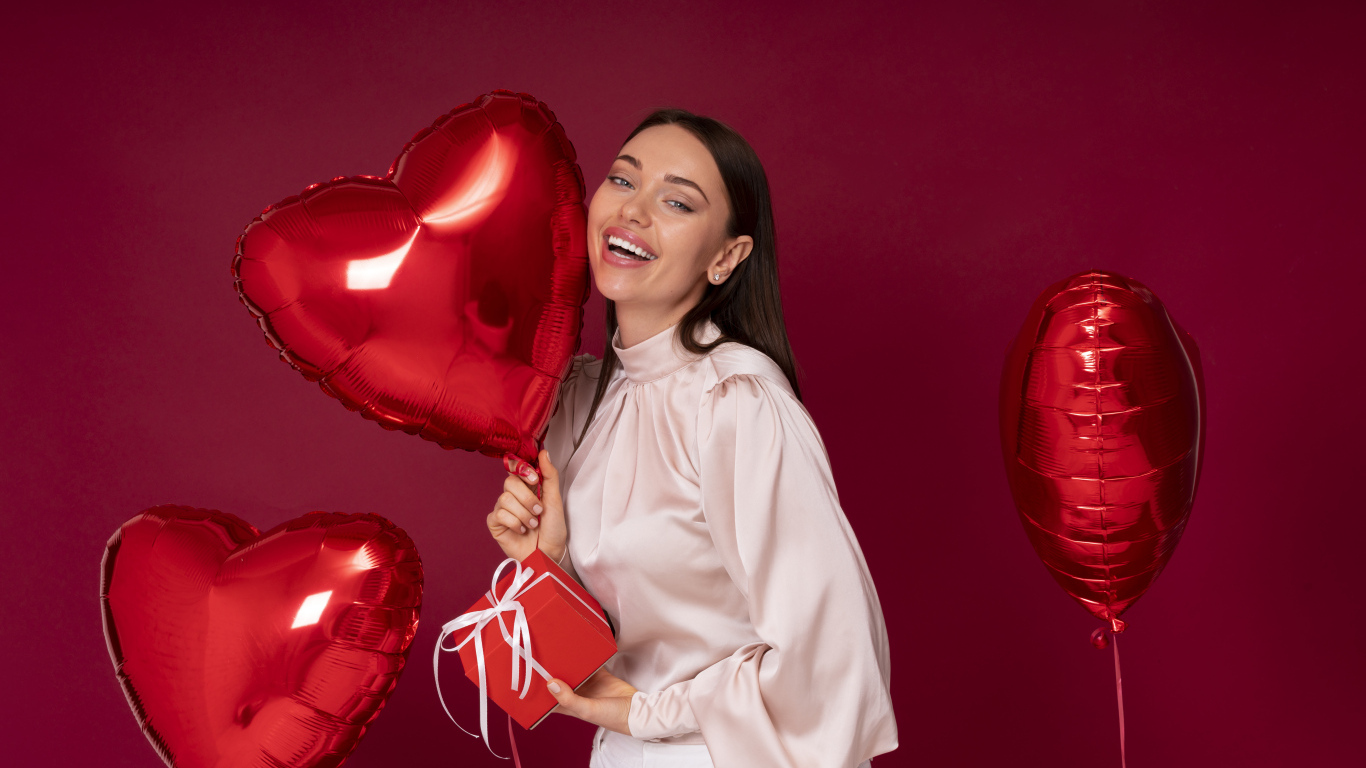 Девушка с шарами в форме сердца на красном фоне