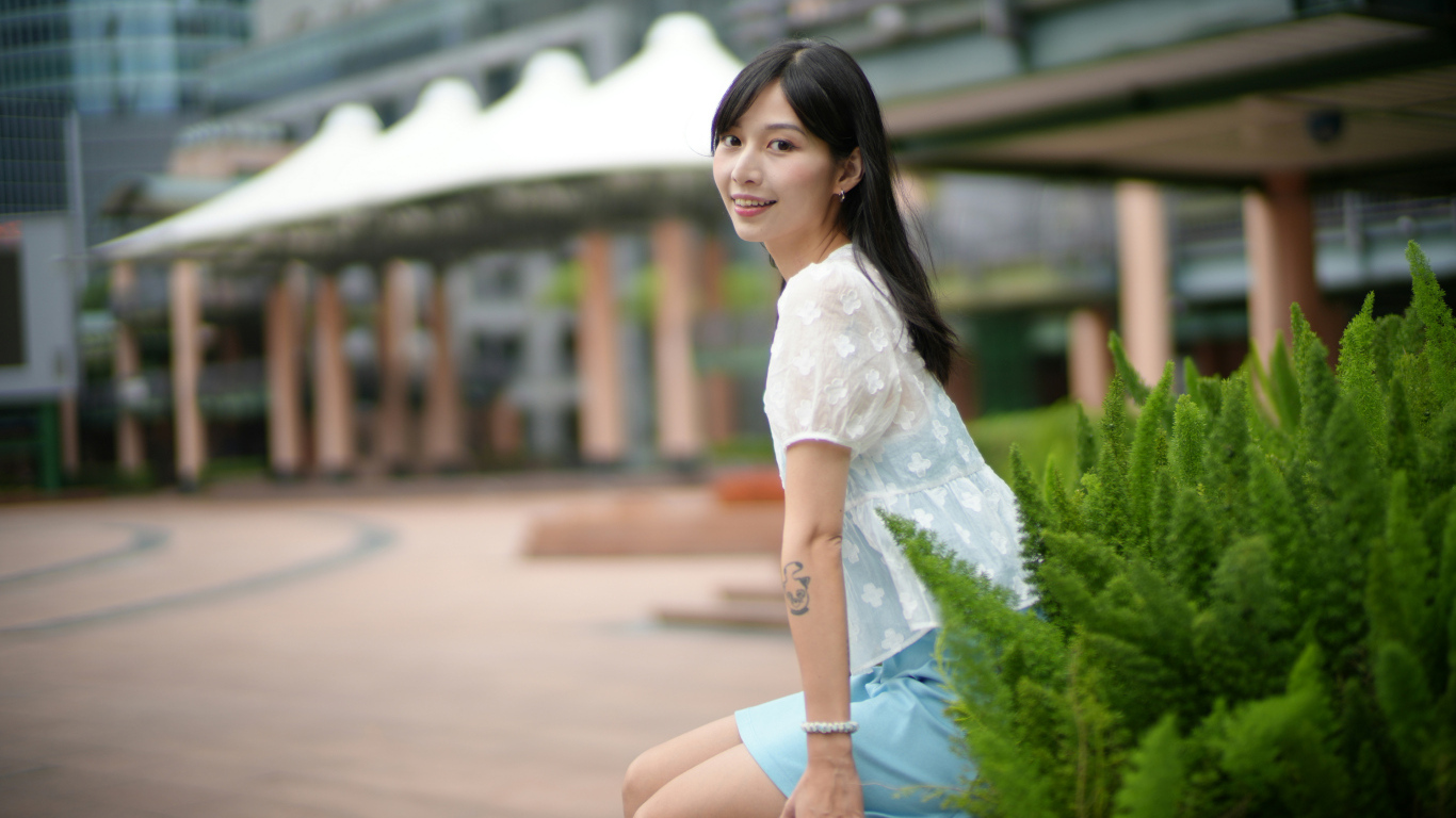 Улыбающаяся азиатка в белой блузке у дома