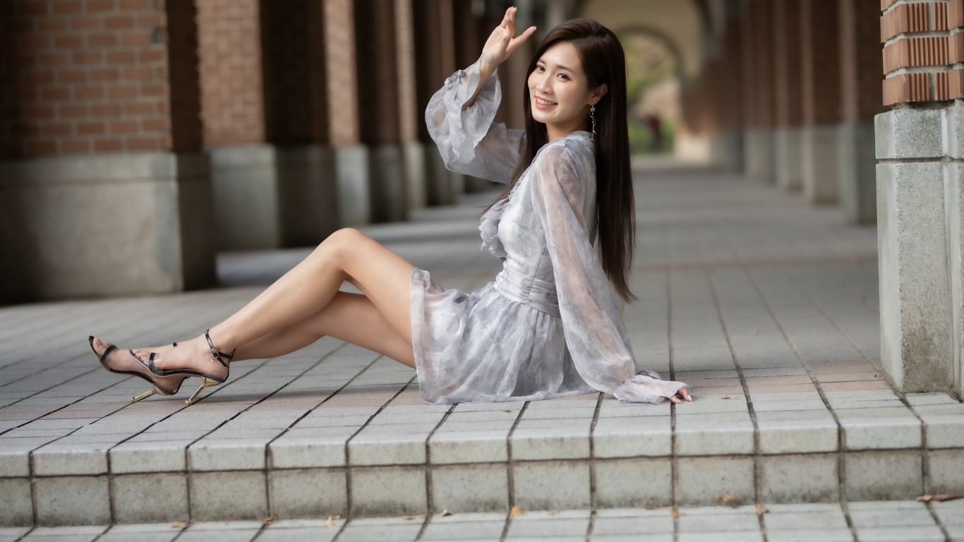 Улыбающаяся девушка азиатка сидит у ступеней