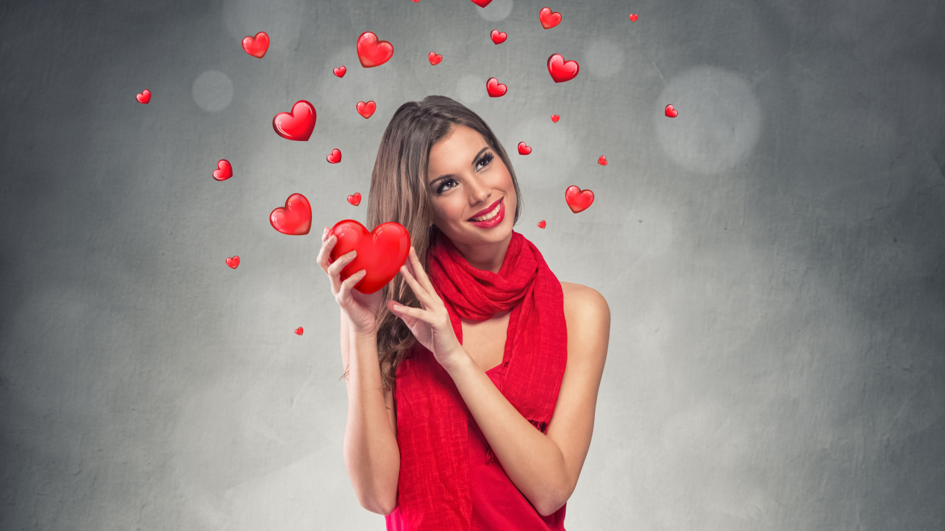 Улыбающаяся девушка в красном платье с сердечками на сером фоне