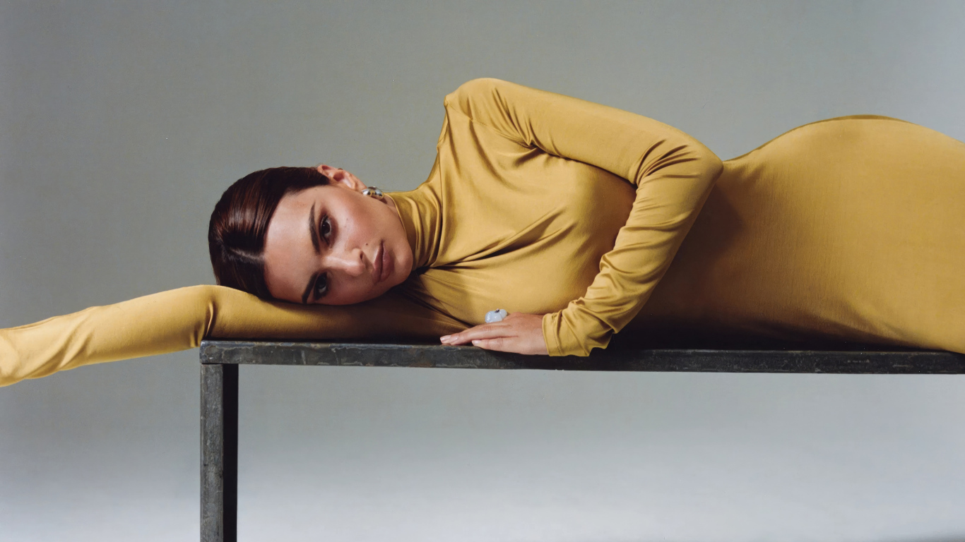 Красивая модель Эмили Ратаковски в желтом платье лежит на столе