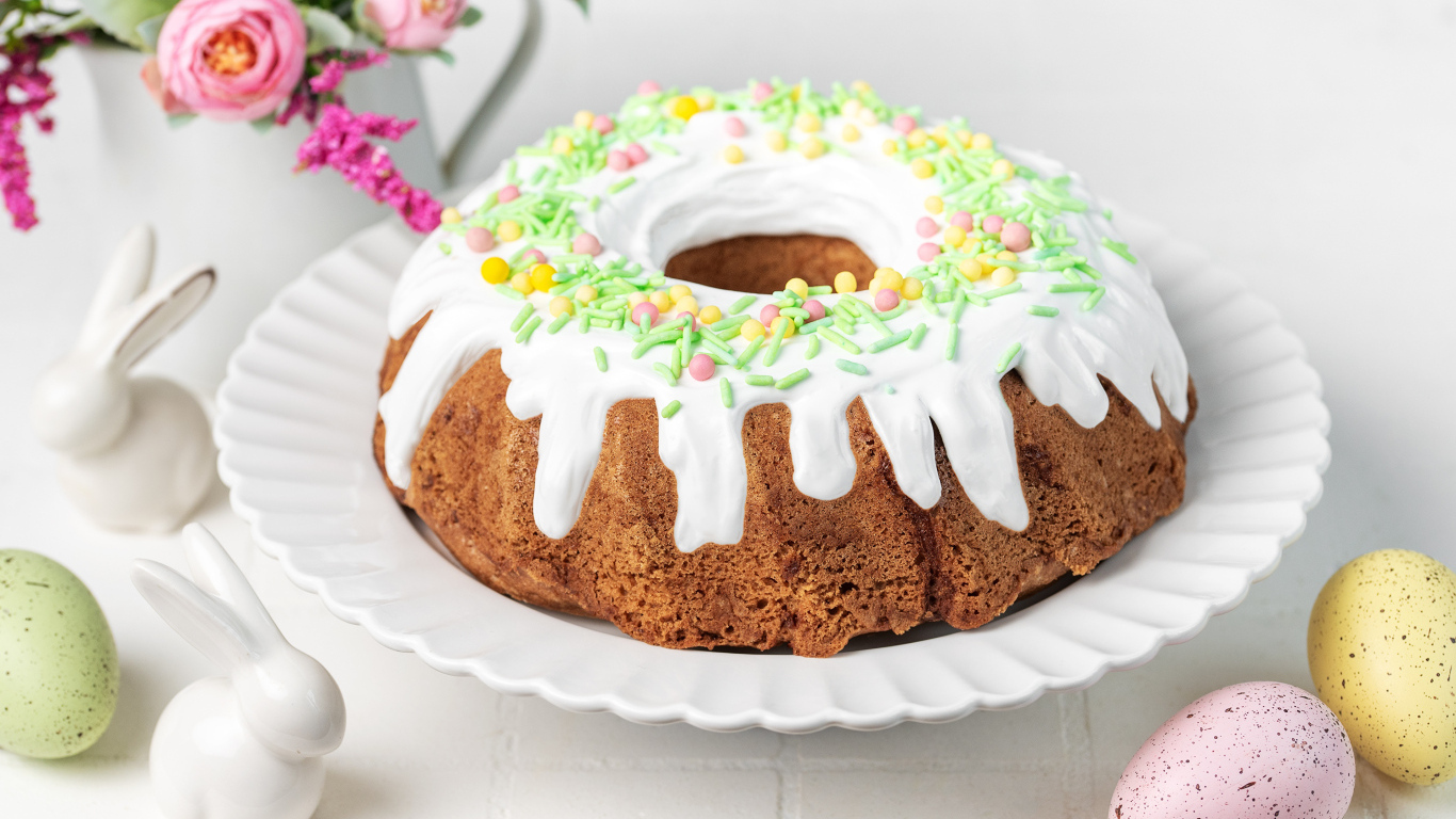 Сладкий пасхальный кулич с яйцами и цветами на столе