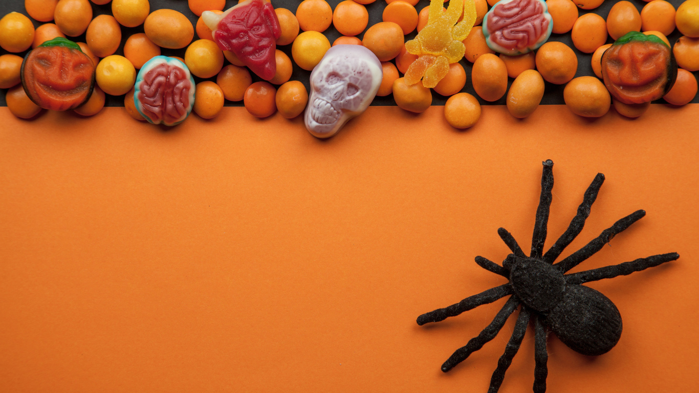 Sweets on an orange background with a black spider for Halloween