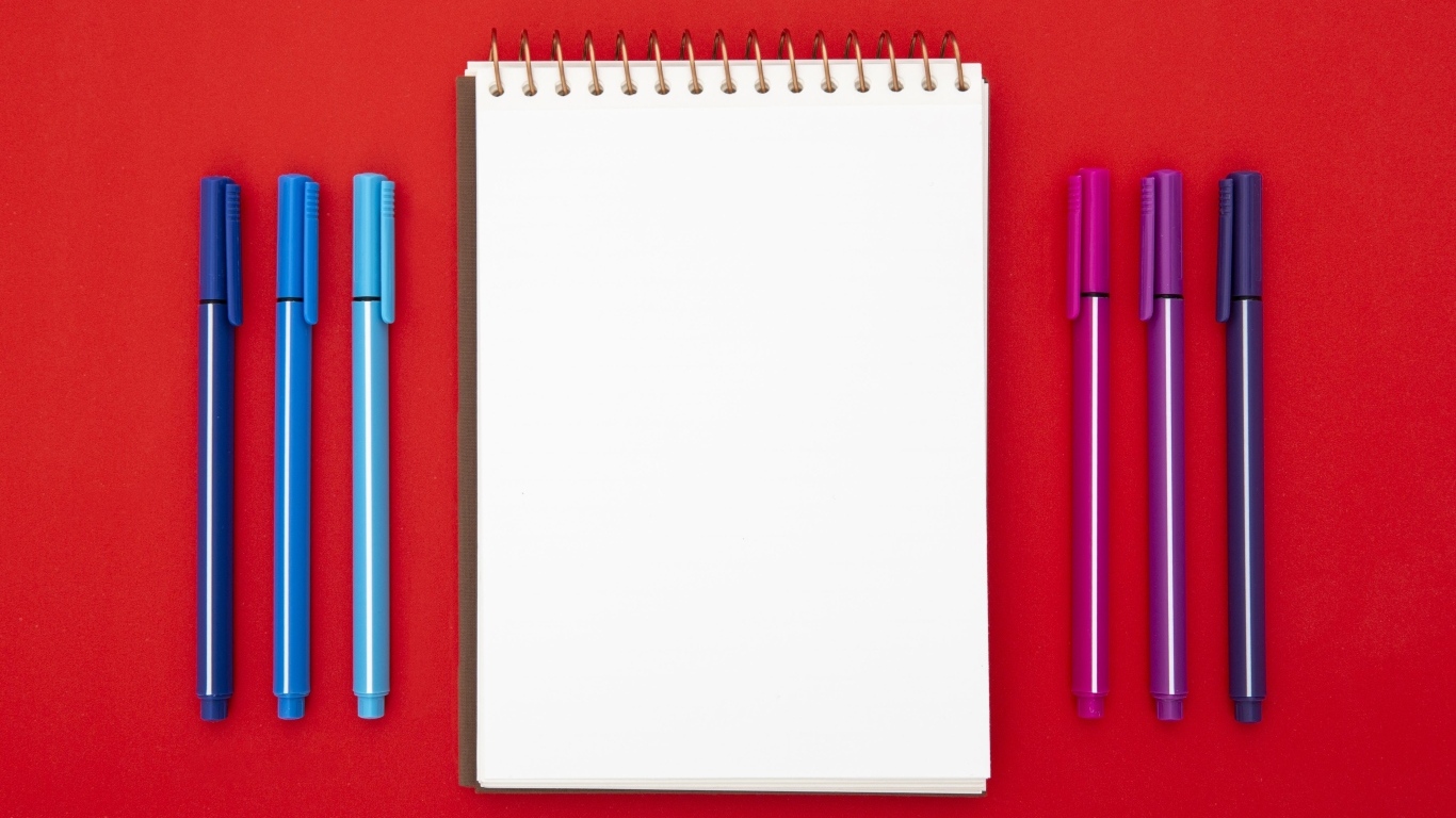 Блокнот и фломастеры на красном фоне