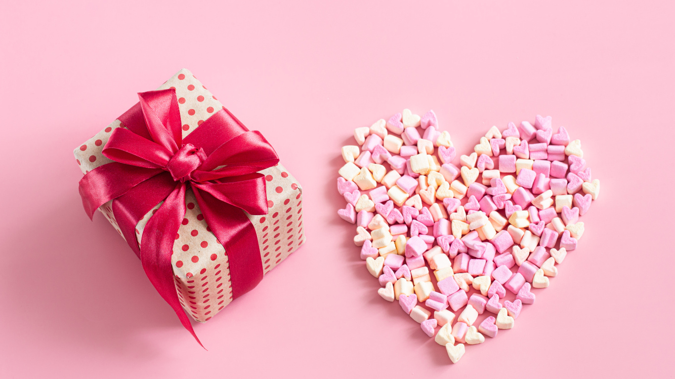 Подарок и сердце из конфет на розовом фоне