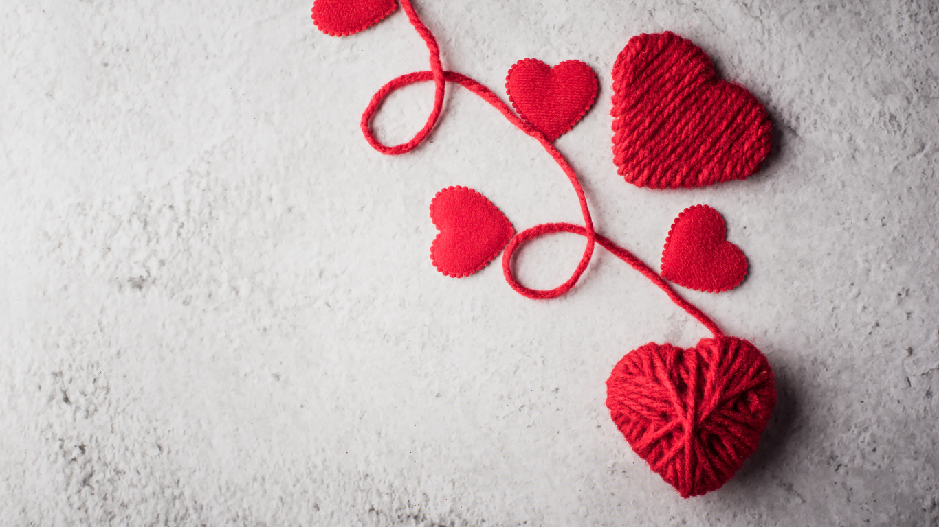Сердечки из красной шерстяной нити на сером фоне