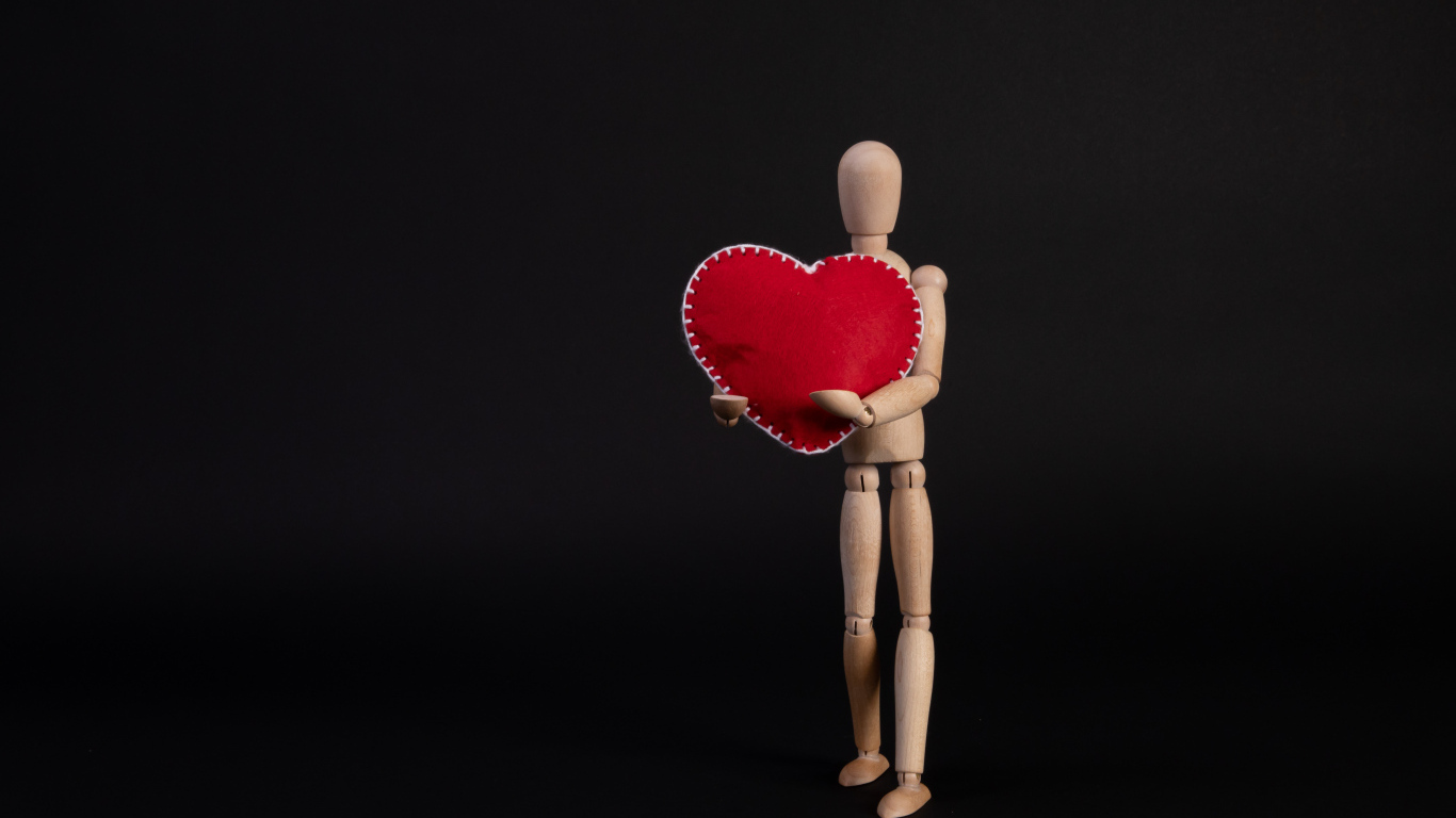 Марионетка держит красное сердце на черном фоне