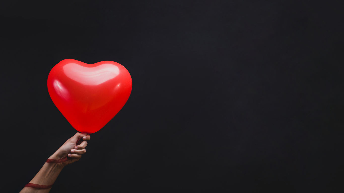 Красный шарик в форме сердца на черном фоне