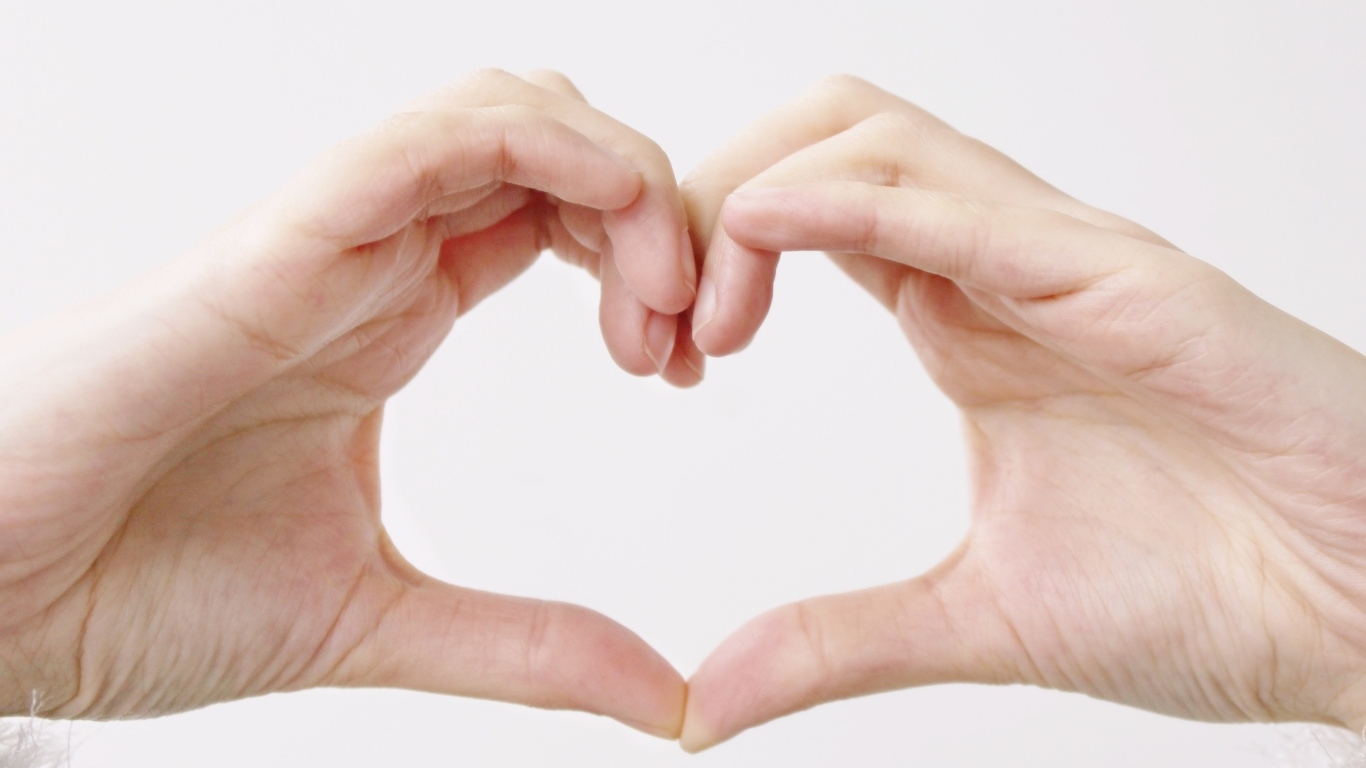Две руки делают сердце на белом фоне