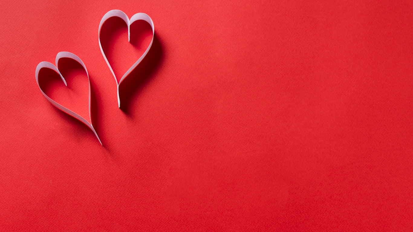 Two white paper hearts on a red background