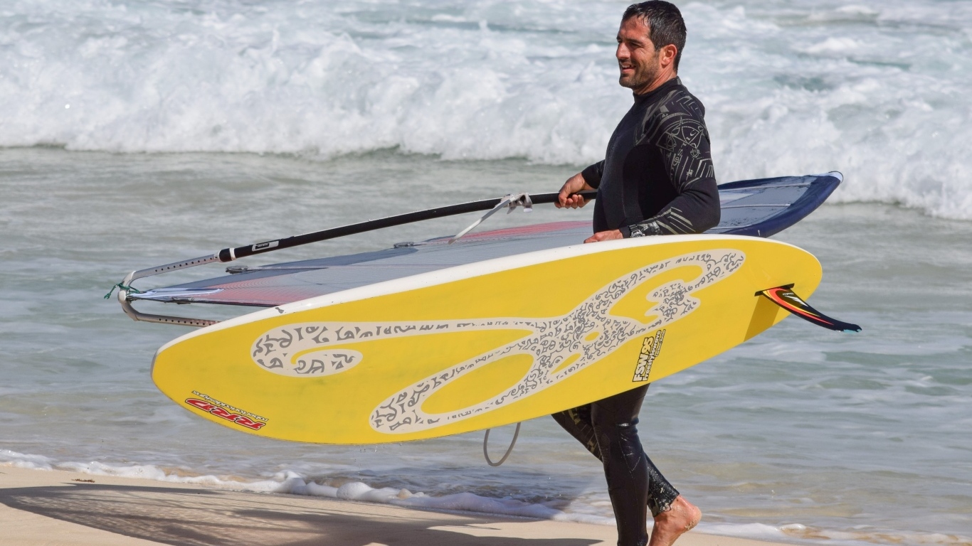 Мужчина серфер с доской на пляже