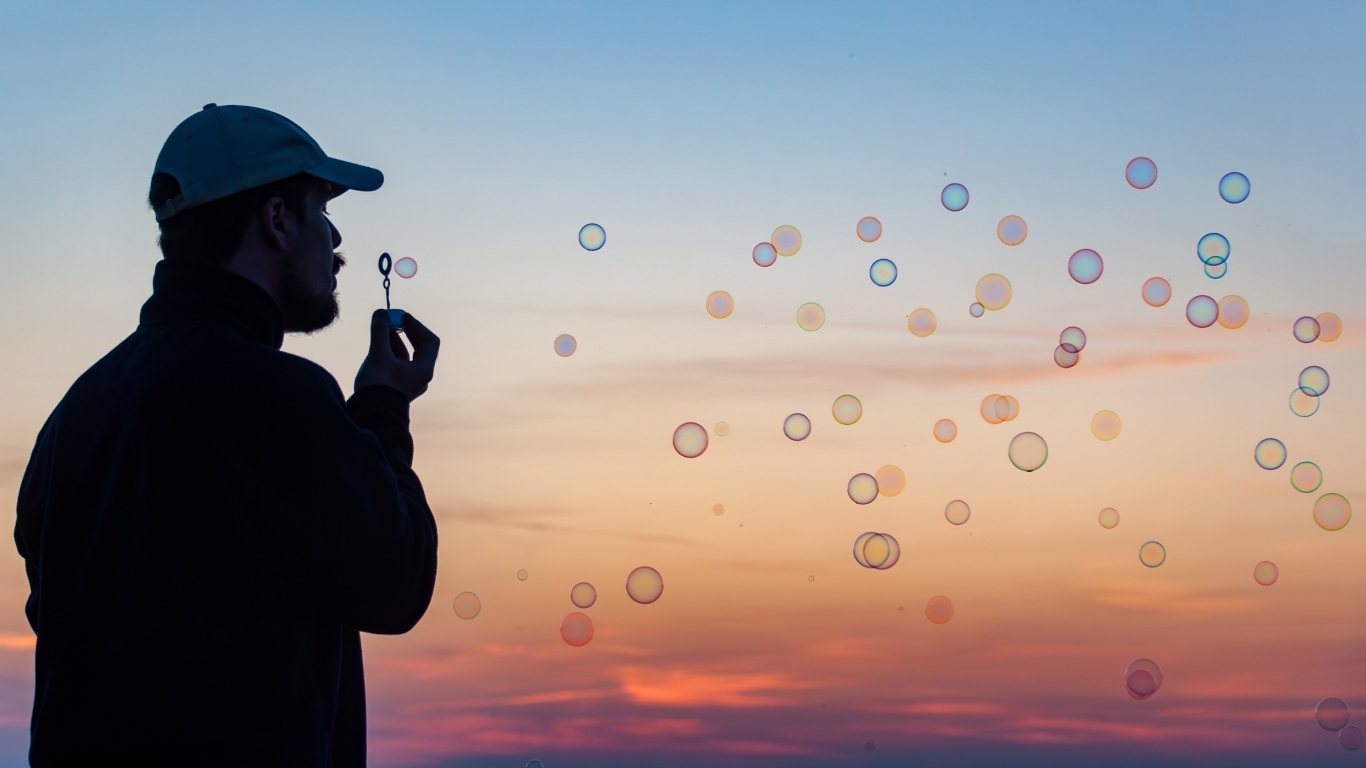 Мужчина пускает мыльные пузыри на закате