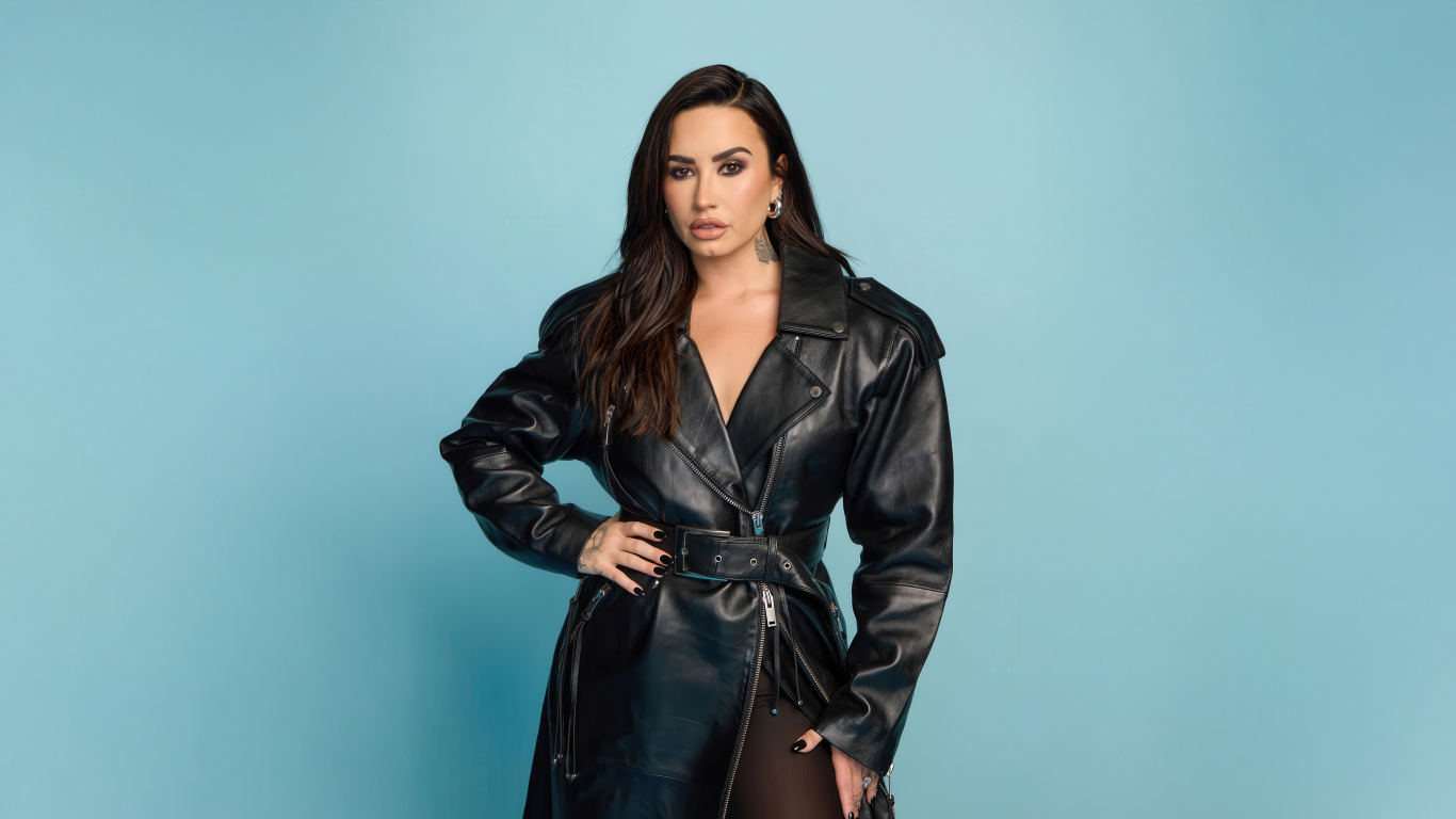 Певица Деми Ловато в кожаном черном пальто на голубом фоне
