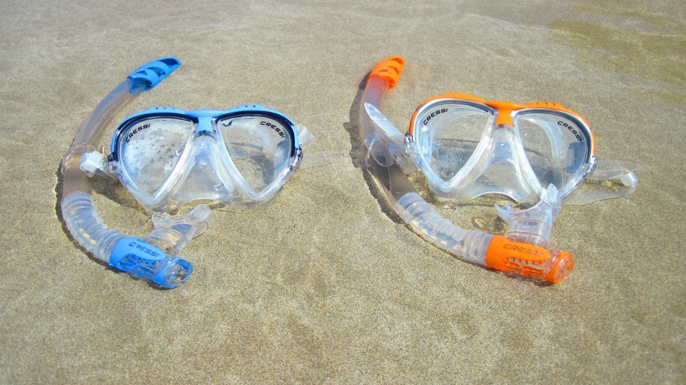 Две маски лежат на мокром морском песке