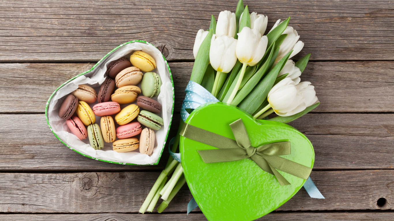 Букет белых тюльпанов на столе с коробкой печенья макарун