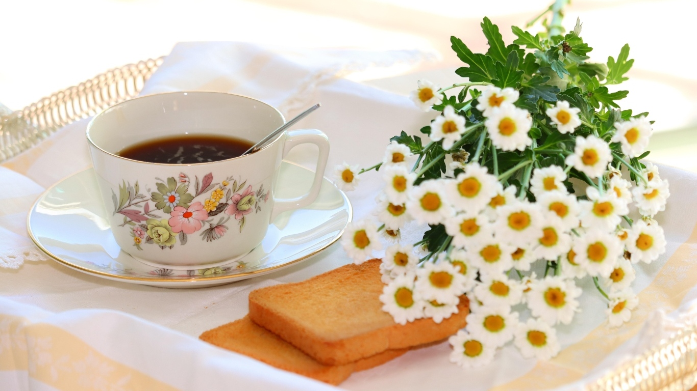Чашка кофе  с букетом ромашек на столе 