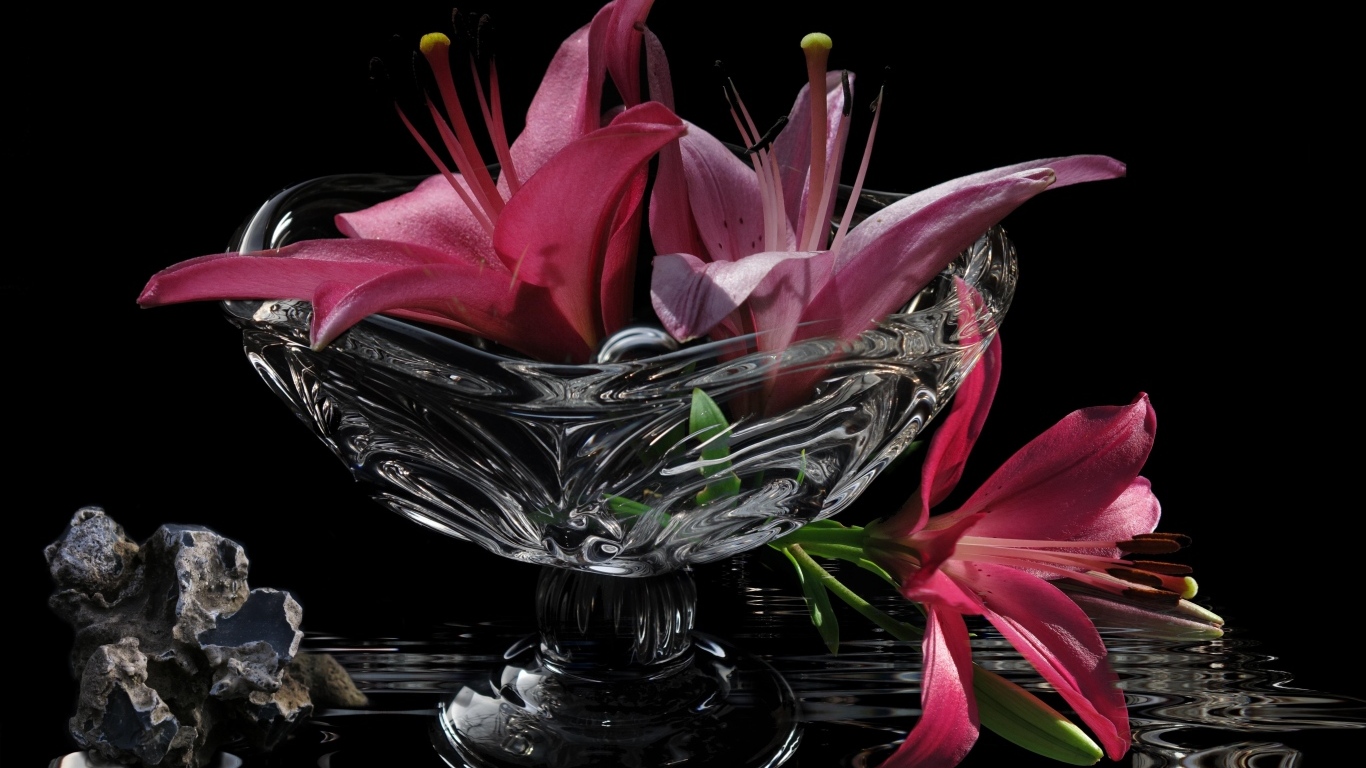 Розовые лилии в стеклянной вазе на столе