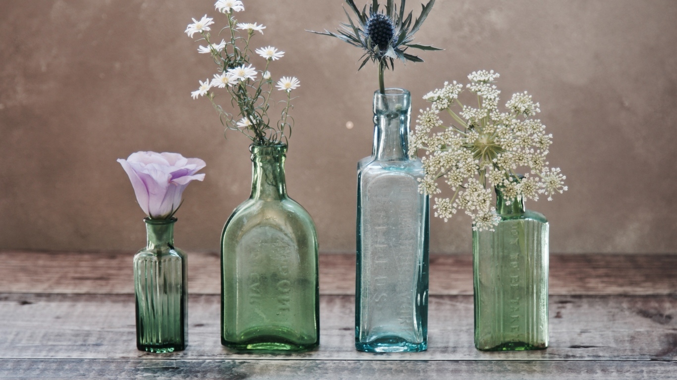 Полевые цветы в стеклянных банках на деревянном столе