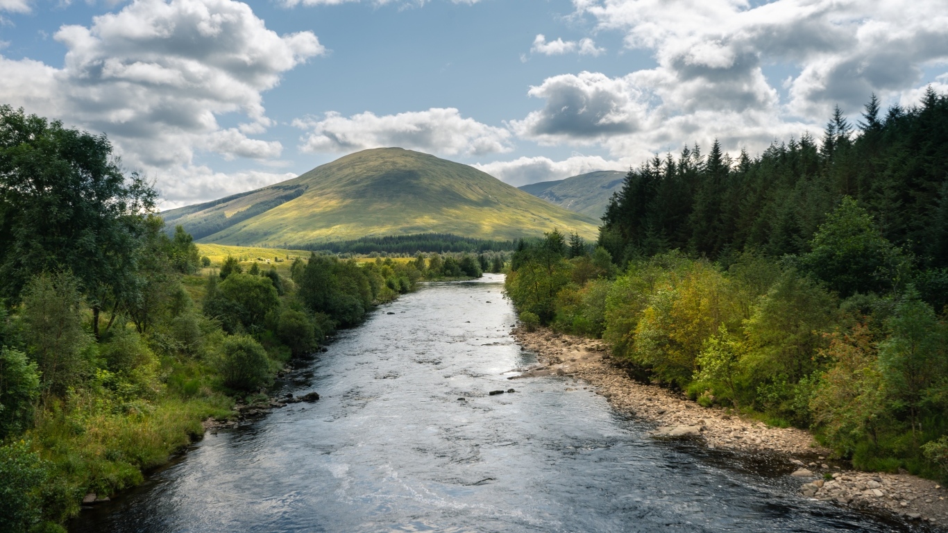 Белые облака в голубом небе над рекой в горах