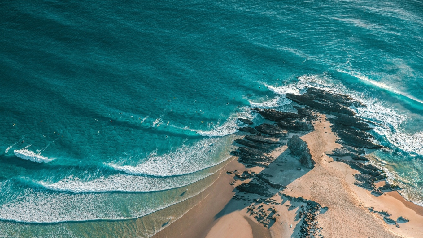 Песчаный берег с большими камнями у океана
