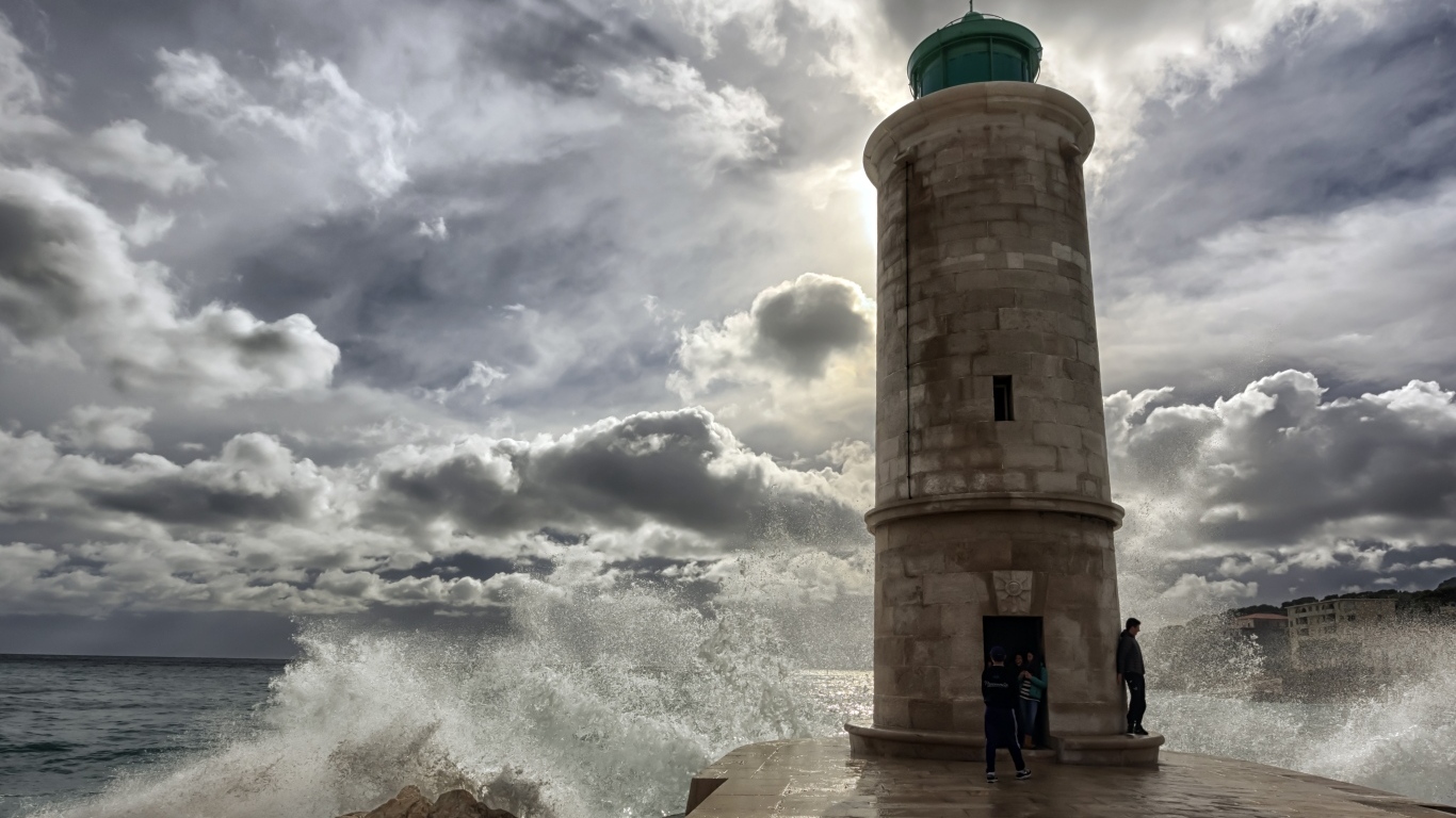 Волны бьются о маяк под красивым небом