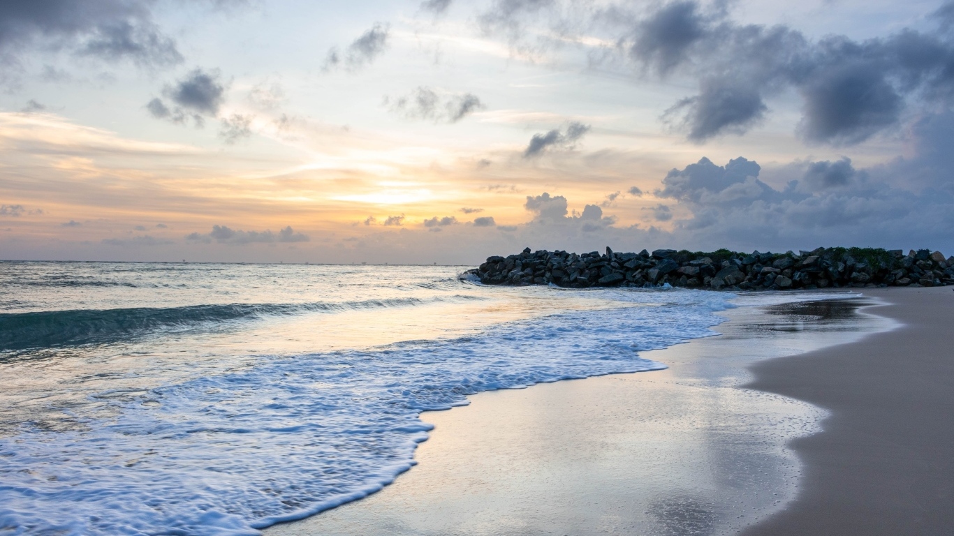 Волны омывают морской песок на рассвете