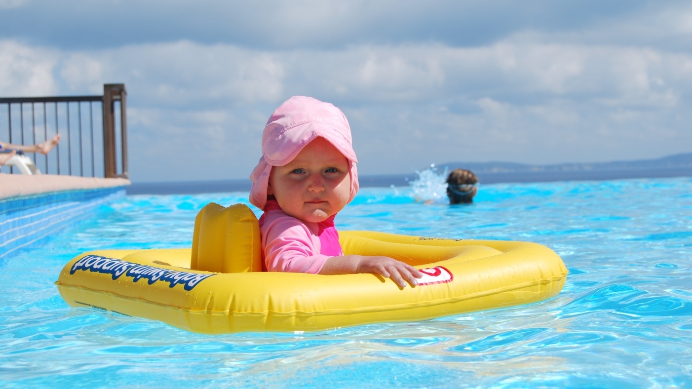 Ребенок со спасательным кругом плавает в бассейне