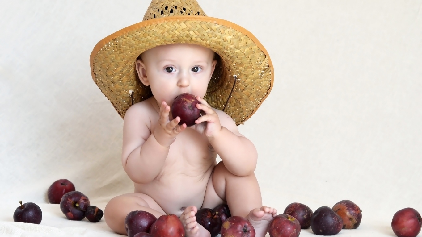 Малыш в шляпе грызет яблоки