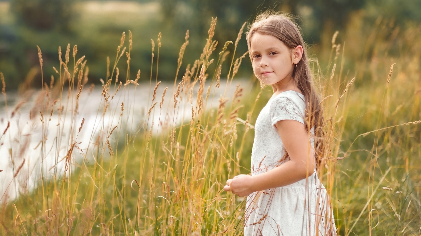 Красивая девочка в белом платье гуляет по траве
