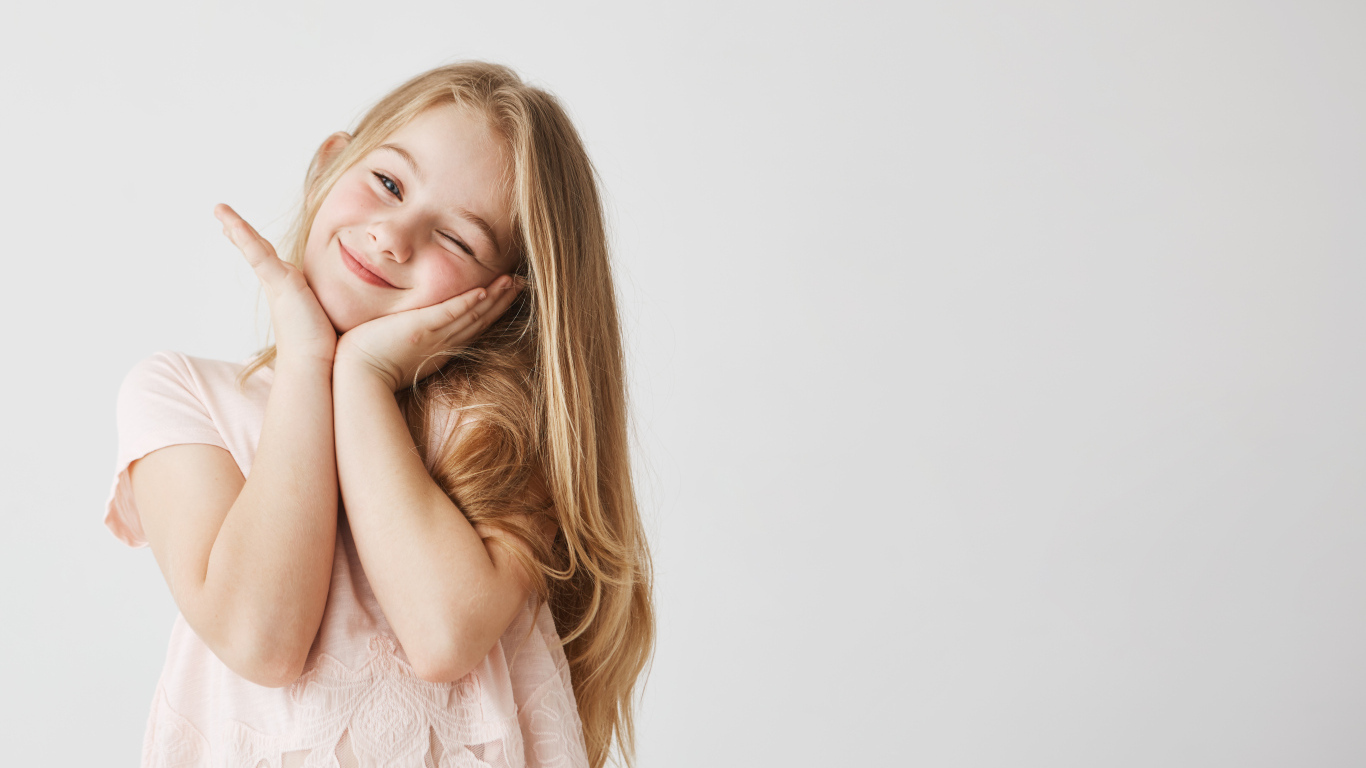 Красивая маленькая длинноволосая девочка на сером фоне